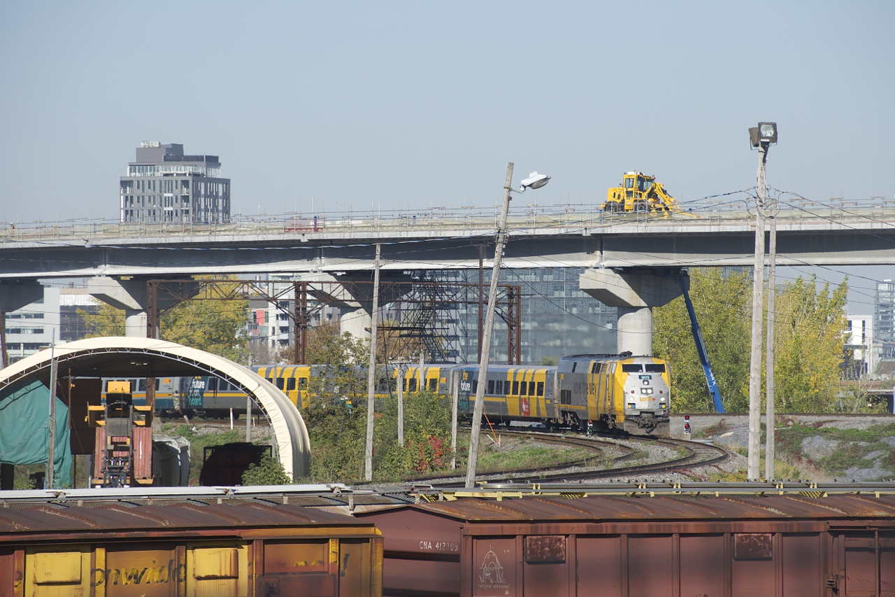 VIA 67 is passing a pair of dwarf signals at Cape, with the one at left showing a Slow to Clear indication for nearby VIA 62. Up above, work progresses on the REM light rail project. A bit to the left two catenary supports from a much older and long out of use electrification project still remain. CN passenger trains through here were electrified from roughly 1940 to 1960.