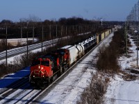 CN 369 heads west with CN 2561, CN 8875 and 124 cars on a frigid winter day. In the distance, counterpart CN 368 is lined on the north track and beyond that, the headlight of CP F95 is barely visible.