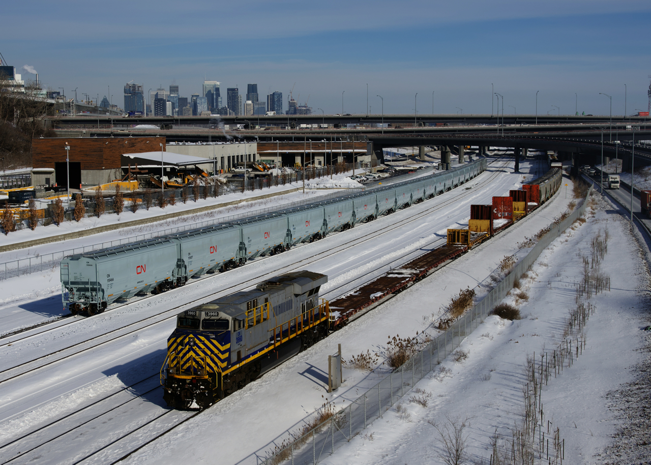 CN 305 has an ex-CREX leader as it passes a string of fresh CN grain cars that are parked on Track 29 of the Montreal Sub.