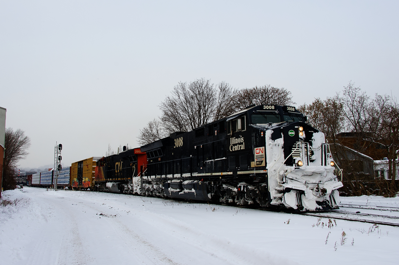 A small bit of flurries are falling as CN 324 passes MP 3 of CN's Montreal Sub with the Illinois Central heritage unit leading and CN 2955 trailing. After serving as the rear DPU unit on a stack train, CN 3008's nose is quite snow-covered.