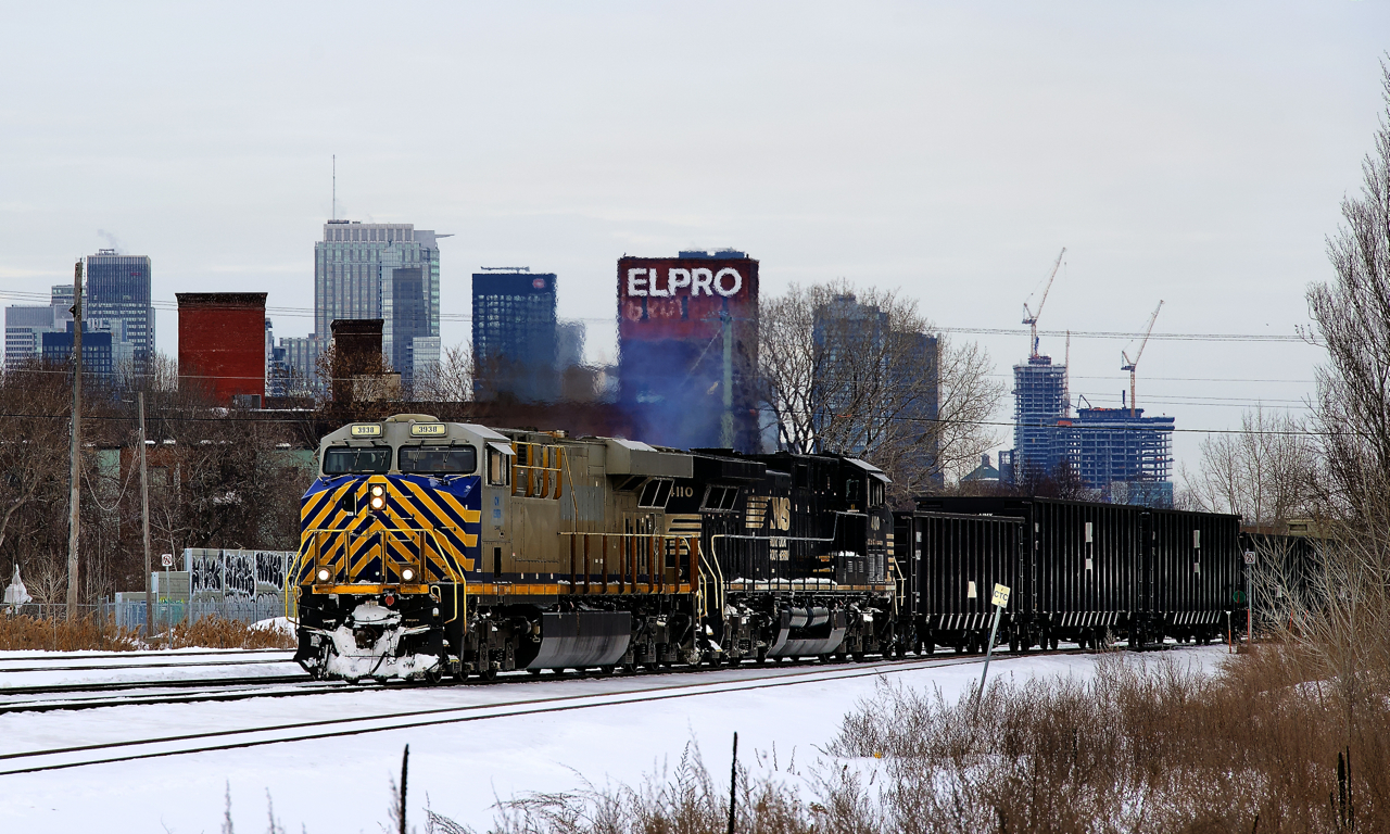 A 114-car CN 305 has power in CREX and NS paint schemes (CN 3938 & NS 4110) as it passes the skyline of downtown Montreal.