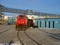 The Hamilton 1500 yard job with CN 4705 and a GP9 is heading into Bunge's parking lot, crossing their industrial lead. The gp9 is crossing over the diamond in this picture, with that track also buried in the pavement. The crew are heading to switch Vopak in the background on this beautifully sunny Winter day.