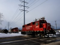 Both CP 4515 and CP 2307 (with cars) are both about to cross Lafleur Avenue at the same time as CP F95 attempts to lift empties from Total Fuel (at left). Iced over flanges would cause them to give up on that.