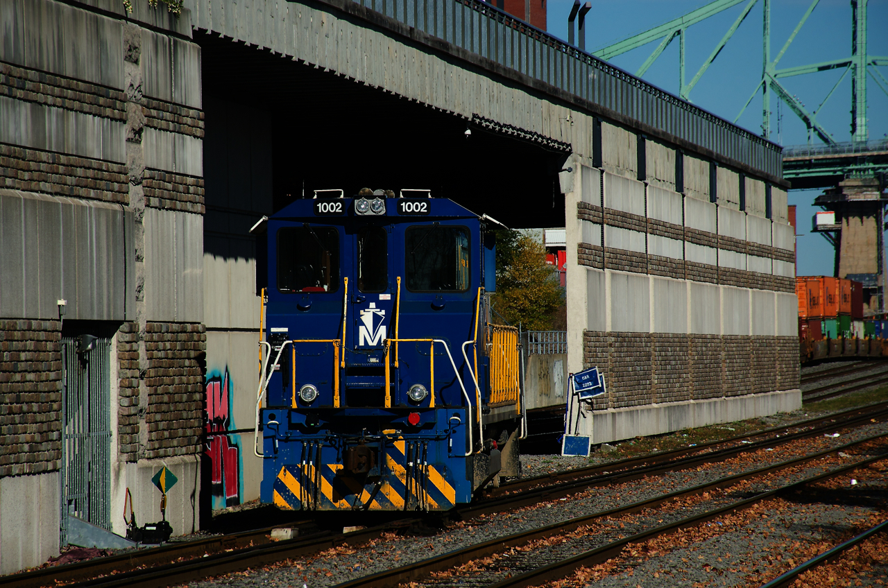 A Port of Montreal switcher sits crewless underneath a park that provides a good vantage point for railway operations in the port.