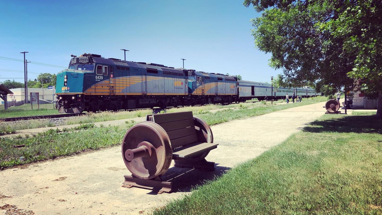 VIA Rail Train 692 headed toward Winnipeg, MB at a stop in Dauphin, MB next to one of the two Dauphin Rail 125 commemorative benches.  Dauphin, MB celebrated 125 years of rail service in 2021 and the benches were placed to commemorate that occasion.