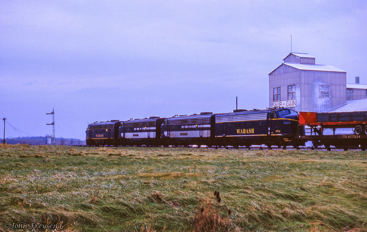 Just over a year after the Norfolk & Western assumed control of the Wabash, Extra 668 west rumbles past the Canada Packers/Shur Gain facility behind a set of Canadian-built GMD F7s.  Note the CN flatbed trailer loaded on the CN flatcar behind the power.  The semaphore signals protected movements at Welland Junction, east of the canal, and presently the site of GIO customer Verbio.  In another few hundred feet, the locomotives will cross the former diamond with the Niagara, St. Catharines & Toronto Railway.Jamie Knott's view of this scene taken in 2020.A shot taken facing the opposite direction in 1964, from the Michael Klauck Collection.Scan and editing by Jacob Patterson.