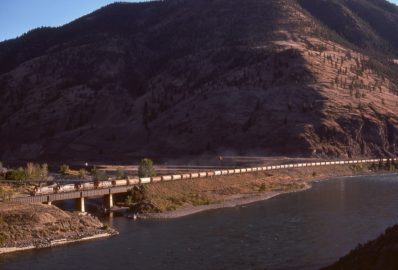 Along the Thompson River just timetable east of Spences Bridge, CP’s Thompson sub. crossed the Nicola River on a straight deck-plate-girder bridge, and on Monday 1977-09-12 at 1756 PDT it was occupied by CN 5141 + 5126 + 5089 + 5274 with eastward grain empties.  While nowadays with a directional running agreement in place in this area it is normal to see CN trains on CP’s track, this was a real variety treat in 1977.

Look closely above about fifteen cars back to see the CP Princeton sub. heading eastward to Merritt, Princeton, and Penticton.