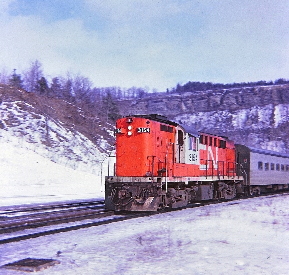 A sunny winter afternoon, CN 3154 with TEMPO paint scheme and coaches flying along westward at Dundas. A "Kodak Instamatic Memory" from long ago.