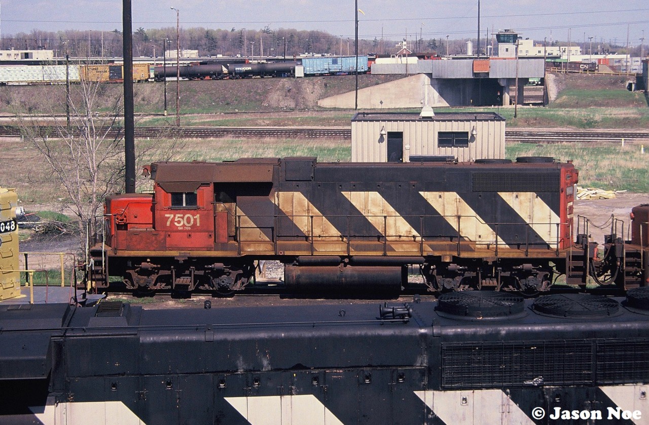 CN GP38-2 7501 is viewed from Toronto’s (Vaughan) MacMillan Yard diesel shop tower awaiting its next call to the hump as another 7500-series set can be seen in the background working the actual hump. To the left is newly built Orinoco Mining SD38-2TC 1048, which was on route from the GMDD plant in London to the AMF facility in Montreal, Quebec for contract painting. This was a mining railroad in Venezuela, that had eight units manufactured and painted in Canada, which were loaded on a ship in Halifax during June of that year to reach their destination. 

So the story goes, checking my notes, this photo was taken during a MacMillan Yard visit thirty years ago on Mother’s Day 1994. With that in mind, I wish a Happy Mother’s Day to every mom out there both here and now gone.