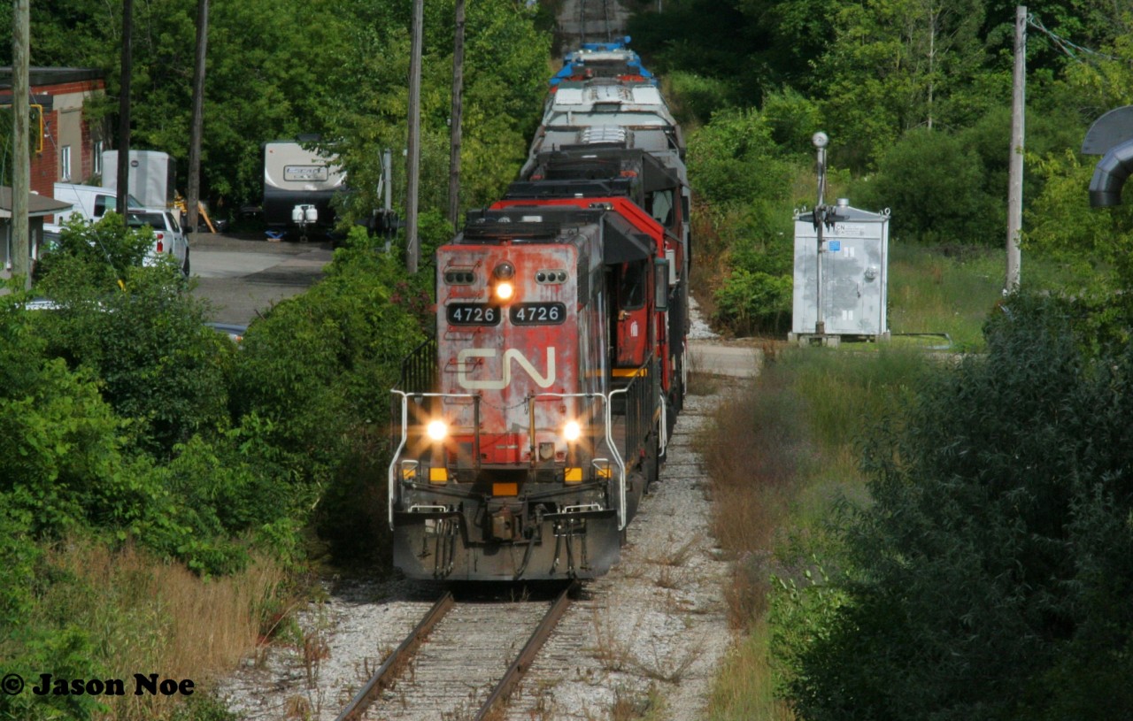 With more units than cars, CN L540 is viewed approaching Stirling Avenue in Kitchener, Ontario on the Huron Park Spur as it heads to the interchange with CPKC on the Huron Park Spur where the crew will lift and set-off. L540 was powered by GP38-2’s 4726, 4732, 4725 and had GP38-2’s 4902 and 7524 on the rear. The latter two units were just along for the ride as they weren’t running and were being sent back to MacMillan Yard in Toronto. July 13, 2023.