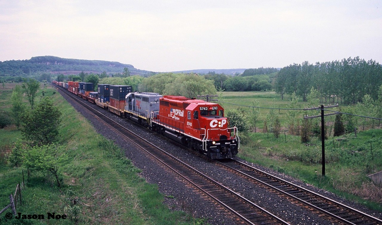 A CP eastbound intermodal train is heading through Milton, Ontario on the Galt Subdivision viewed from the hillside of the CN Halton Subdivision. The consist included freshly repainted CP SD40-2 5743 and Precision National (PNCX) SD40 3107, which was ex-UP 3107. At the time, CP had a group of 7 PNCX SD40’s leased as part of their rapidly expanding mid-90’s lease fleet.