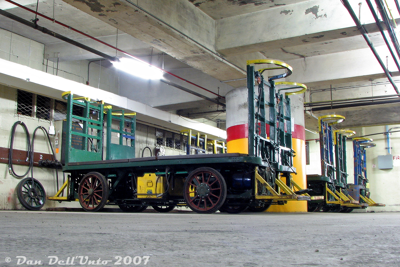 Not somewhere you'd have access to on a normal tour of Toronto Union Station:

Buried under the bustling platforms and station concourses, down amid the underground tunnels, access corridors and parking garages, was the maintenance area for VIA Rail's fleet of ancient electric battery-powered baggage carts that served their trains arriving and departing Union Station. A full house of green and blue carts sit parked in their bays, while the walls are lined with charging outlets, power cables, and spare parts. More modern equipment including a small forklift and pull-tractor sit nearby out-of-frame. When in use, the carts could be found stationed empty on the platforms upstairs awaiting an incoming train, or fully loaded up to their top bars with luggage bags, suitcases, duffle bags and other large pieces of travel baggage.

According to the Toronto Railway Historical Association's website, the old electric battery powered baggage carts were built in the 1920's by the Elwell Parker Electric Company for use at Union Station when it was brand new. They were pedal and lever-operated, and could be controlled from either end by a baggage handler. One of the green carts would later be donated by VIA Rail to the TRHA in 2014 (judging by spotting features, it may be the second one in). It's unlikely any of the others remain in operation today, replaced by more modern equipment.

The rare-access weekend Union Station tour that included a visit to the unused upper offices of Union Station, the underground corridors, and a tour of the shuttered ex-CPR John St. Roundhouse (before the museum opened, and before much of the then-untouched roundhouse was converted to house Leons) was courtesy the Toronto Railway Historical Association, organized for the visiting Guelph Historical Railway Association, and guided by the late Toronto railway historian Derek Boles (who was a wealth of knowledge, and known for his numerous published historical railway articles and regular Union Station tours). A number of RP.ca contributors were also in attendance that day.