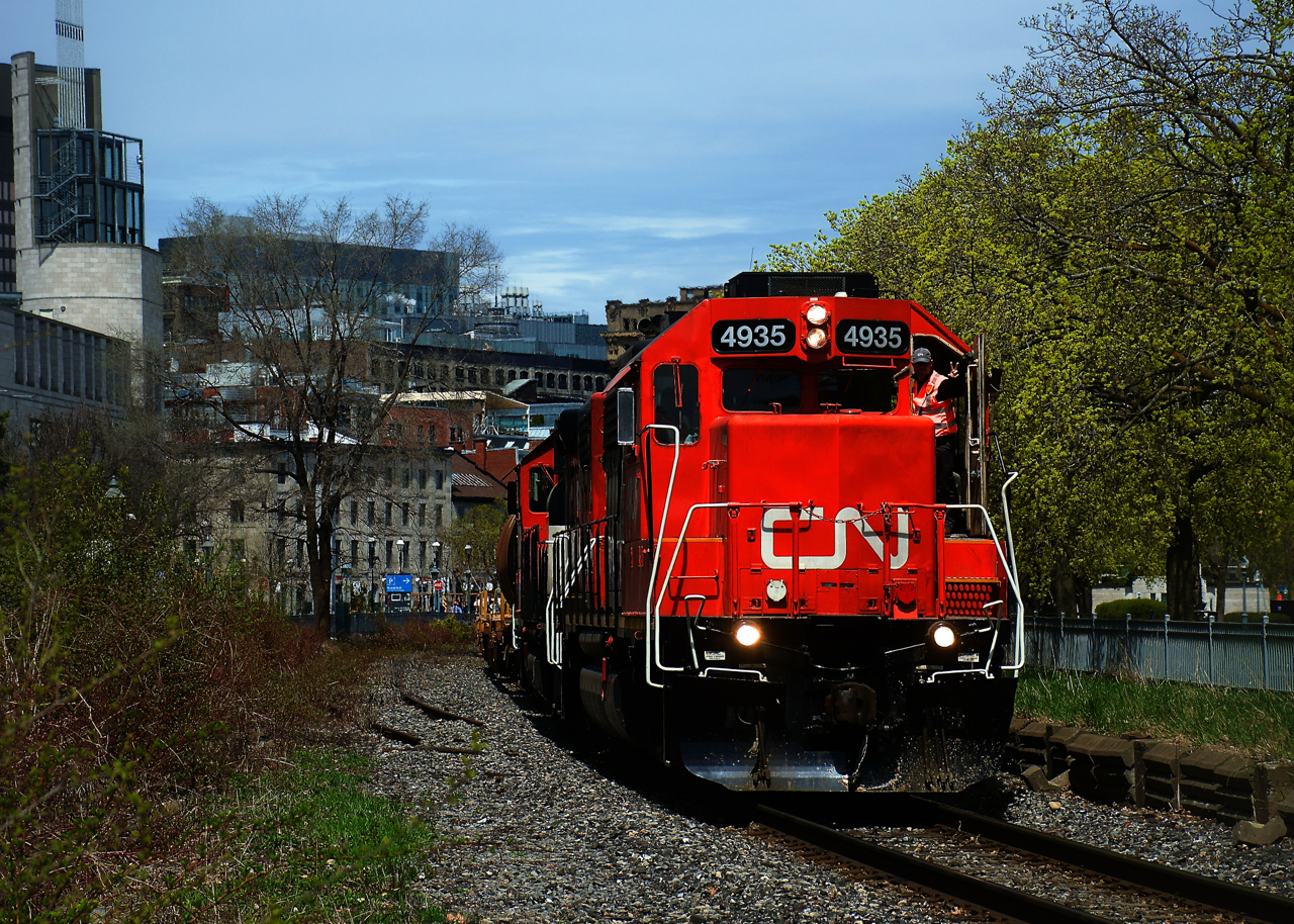 A crewmember gives the peace sign as CN 500 leaves the Port of Montreal with a single hopper followed by baretables.