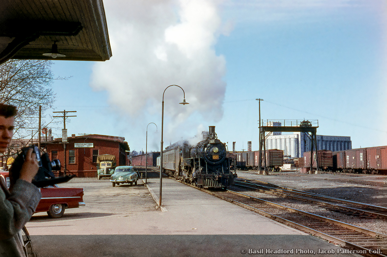 CNR mixed train M339 arrives at Owen Sound behind H-6-c, 4-6-0 1525, built in 1908 for the Canadian Northern Railway.  Despite only having a combine in tow, this equipment was used on a total of six trains in a little under six hours, six days per week over the ten mile long Wiarton Subdivision.

Train M340: Owen Sound - Park Head
Train M341: Park Head - Wiarton
Train M336: Wiarton to Parkhead, connecting with train 173 from Hamilton, and 174 from Owen Sound
Train M337: Park Head - Wiarton
Train M338: Wiarton - Park Head
Train M339: Park Head - Owen Sound

Filling out the scene is the CNR freight shed, classic automobiles, the Grand Trunk era transload crane, and Owen Sound's large grain elevator, completed in 1925




Basil Headford Photo, Jacob Patterson Collection Slide.