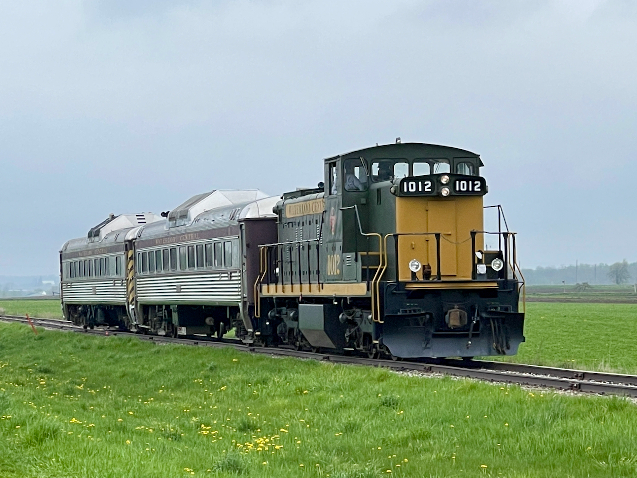 On May 5, 2024, the TH&B Historical Society departed from the Waterloo Central Farmer's Market Station in St. Jacobs at 1:00pm for a train ride to Elmira.  We had two run pasts on the return trip just south of Elmira.  Arriving at the Waterloo Central shops, we all detrained for a presentation by the general manager Bob Fallowfield on the operations and future plans for the railroad.  Coffee and doughnuts were supplied by the TH&B Historical Society.  Hats, shirts and memorabilia were on sale and a raffle was held for various items.  Proceeds from the member donations was presented to the Waterloo Central in thanks for their hospitality.  A group photo was taken with a TH&B caboose as the backdrop.  All aboard again to return to the Farmers Market Station for 4:00pm.