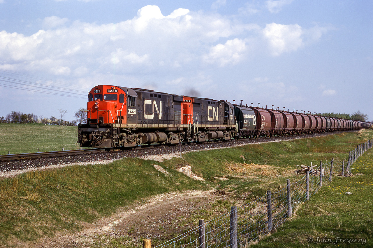 Returning north to Adam's Mine on the Ontario Northland Railway, an empty Dofasco ore train flies along the Bala Subdivision just north of Udney.Scan and editing by Jacob Patterson.