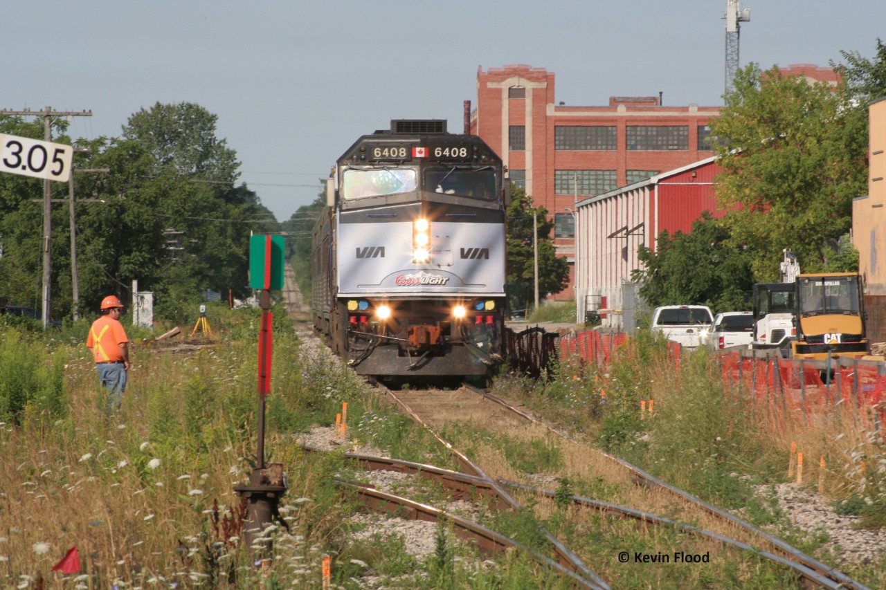 In August 2011, a surveyor looks on as VIA 84 eases towards its station stop at Kitchener with VIA 6408 in a Coors Light wrap. This location is now Kitchener West, where the Guelph Sub crosses King St. and is the junction with the Huron Park Spur (the tracks curving out in the foreground). In this photo, there is evidence of the early stages of redevelopment of this area to its current state, including the staging tracks of the GO trains (at right of photo). Later that year, GO trains would begin running as far west as Kitchener. You can also see the grade of the line towards present day station sign Sturm. It's fascinating how much Kitchener-Waterloo has changed since I was a kid.