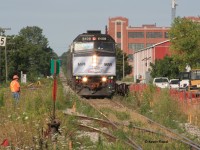 In August 2011, a surveyor looks on as VIA 84 eases towards its station stop at Kitchener with VIA 6408 in a Coors Light wrap. This location is now Kitchener West, where the Guelph Sub crosses King St. and is the junction with the Huron Park Spur (the tracks curving out in the foreground). In this photo, there is evidence of the early stages of redevelopment of this area to its current state, including the staging tracks of the GO trains (at right of photo). Later that year, GO trains would begin running as far west as Kitchener. You can also see the grade of the line towards present day station sign Sturm. It's fascinating how much Kitchener-Waterloo has changed since I was a kid.