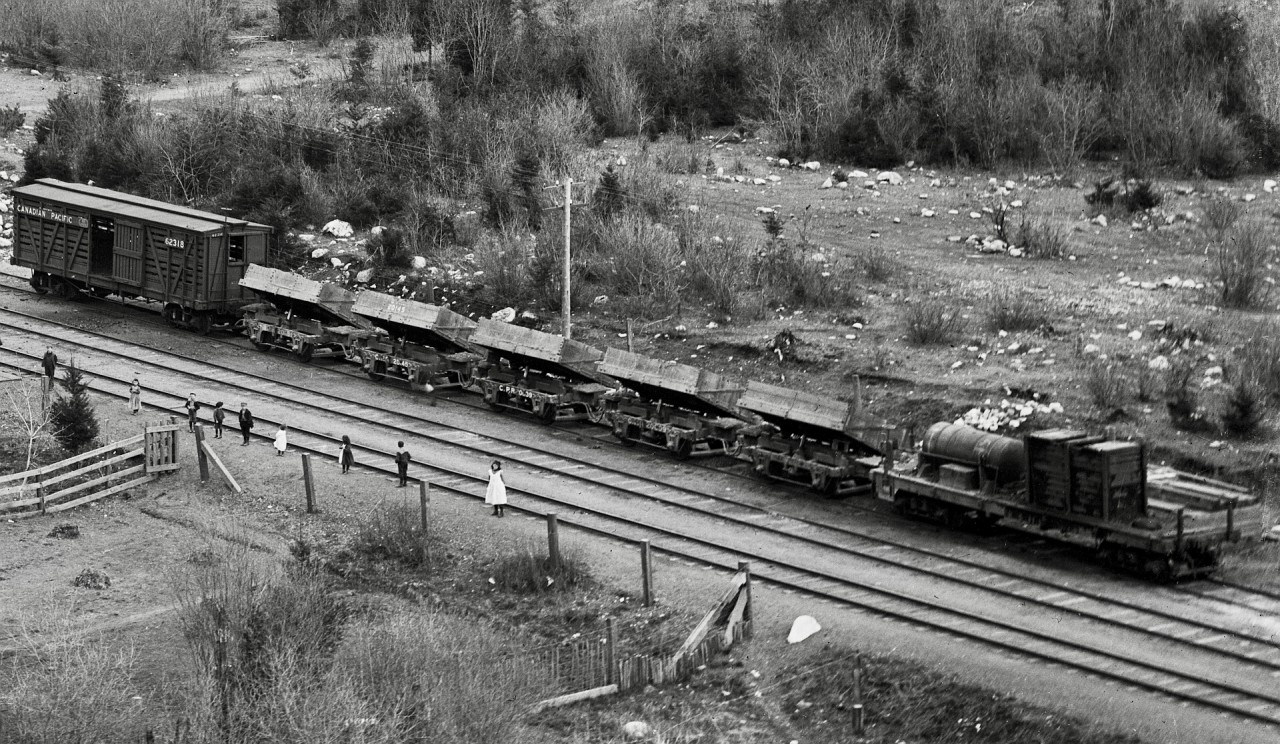 As a second example of the astonishing level of detail in the Archibald Murchie glass negative of Keefers recently posted (http://www.railpictures.ca/?attachment_id=54515), consider this extreme crop to another group of cars near the depot.

Probably stored tipped to avoid accumulating precipitation, those side-dump cars are something never seen before, simple predecessors of the air-dumps common today.

The nine people facing the camera are likely a significant part of the population of Keefers, which was probably still known as Keefer’s in those days.