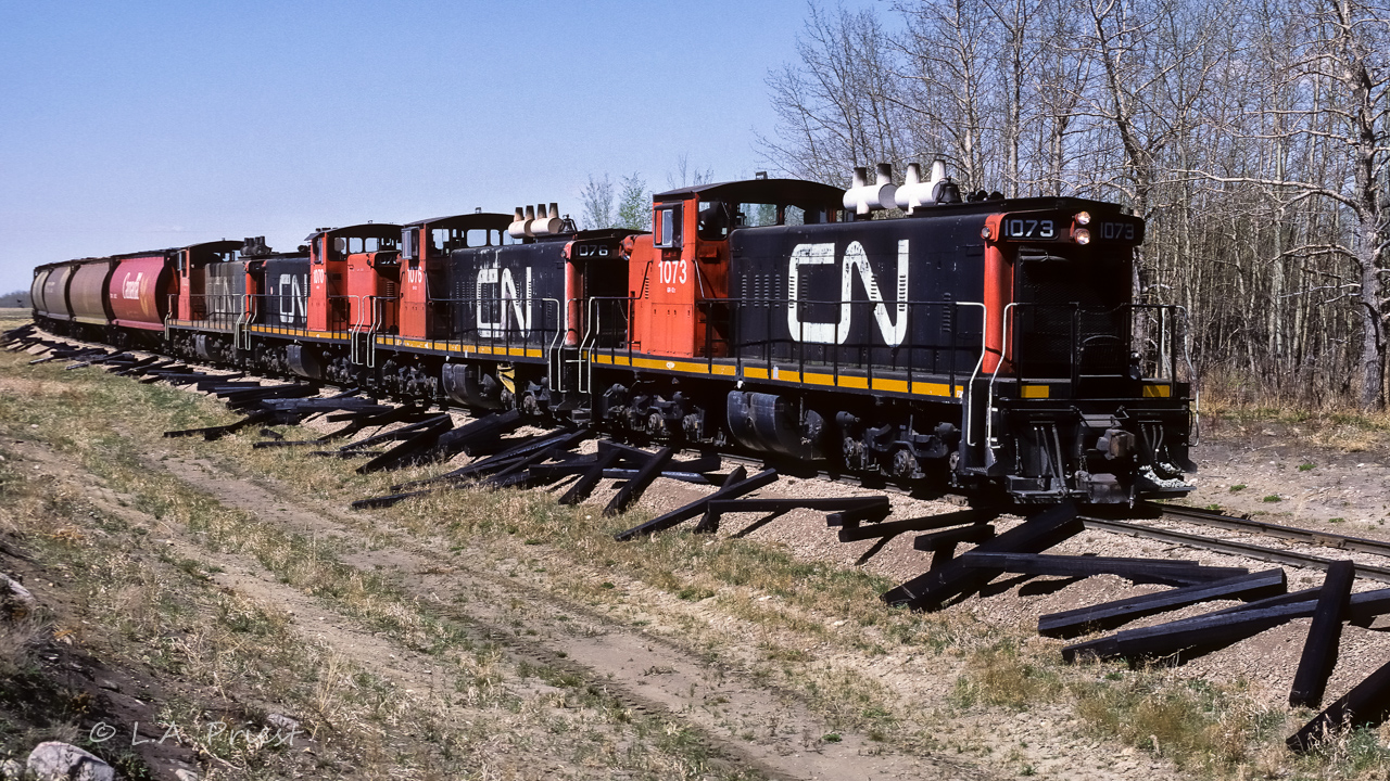 Another photo from May/88 showing the amount of work being done on the track. A lot of ties to be replaced in this scene, a lot of those old ties ended up on our golf course. Tee boxes, shoring up bunkers, etc. This picture shows the grain extra returning to Edmonton with a train of hoppers nowhere near big enough to need 4 engines. The unit at the very back is the 1002, which I believe, had spent recent time working on the west coast. Possibly it had come to Edmonton for repairs and was out on on a test run before heading back. Photo time was 14:45.