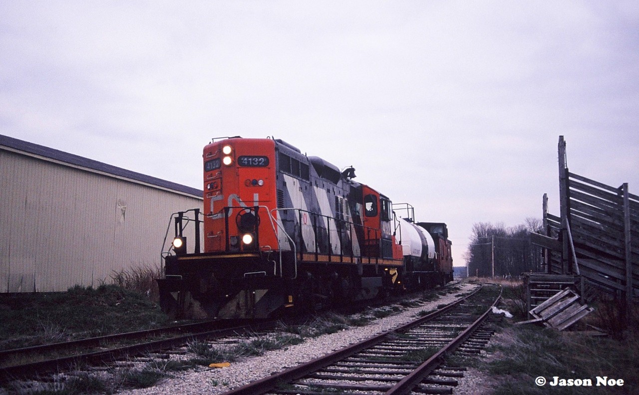 CN GP9RM 4132 leads the 15:30 Kitchener Job by the old St. Jacobs Farmers Market stock pens approaching King Street in north Waterloo, Ontario. The job has one tank car for Sulco in Elmira on the Waterloo Spur.