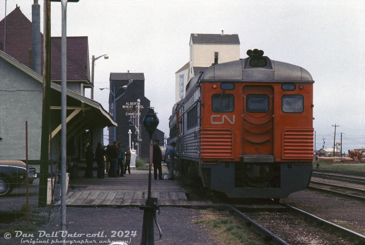 CN RDC-1 6114 has arrived at Camrose Station from Drumheller (on the Drumheller to Edmonton "Railiner"), and has made its station stop. Now, CN RDC-3 6356 on the Calgary-Edmonton train has come out of the siding (note switch stand in the foreground) and both are being coupled together by the crew in order for the two trains to to make the combined run together from Camrose to Edmonton.

This view offers a better angle of the station platform, and the end fluting of 6356 (the only CN RDC so equipped in the fleet, originally built for the MKT and acquired thirdhand from the C&O). Also note the old 51st Avenue grade crossing (now an underpass), and the old wooden grain elevators in the background for United Grain Growers (UGG) and the Alberta Wheat Pool (the latter remains to this day, still getting rail service).

6356 by the station platforms: http://www.railpictures.ca/?attachment_id=54598
6356 side view: http://www.railpictures.ca/?attachment_id=54622

Original photographer unknown (possibly E.W.Johnson), Dan Dell'Unto collection slide.