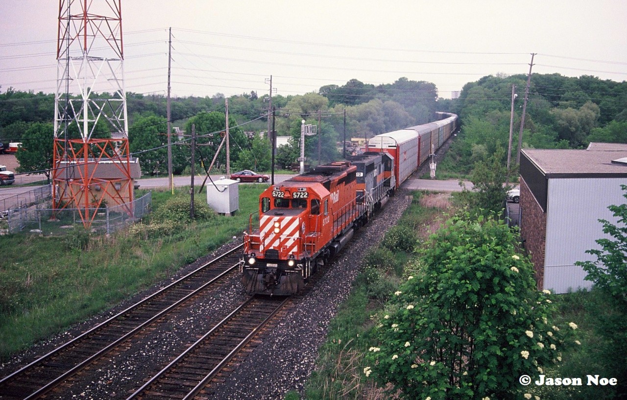 A CP westbound train is heading through Milton, Ontario on the Galt Subdivision viewed from the hillside of the CN Halton Subdivision. The consist included CP SD40-2 5722 and HATX GP40-2 512, which is former Boston & Maine 300. At the time, CP had a large group of Helm Financial Corporation units leased as part of their rapidly expanding mid-90’s lease fleet.
