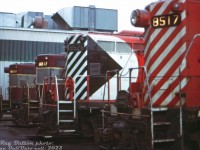 CP Rail GP9's 8517, 8526, 8817 and 8511 sit parked outside the Alyth Yard diesel shop in Calgary awaiting attention from shop forces. Two sport the newer "Action Red" livery with end stripes and large multimark, while the other two retain their 1960's maroon & grey "Script" livery.<br><br>Most of CP's GP9 fleet was based out west, specifically assigned out of Alyth, Winnipeg, and later Nelson. The three 8500's here were Alyth-assigned dual freight/passenger units, part of a group equipped with steam generators (8501-8529) for use as passenger protection power on The Canadian and other passenger trains CP operated. Dynamic brakes enabled them to be used west of Calgary on the mountain grades, and the split 800/800gal fuel & water tanks underneath necessitated the air tanks (or "torpedo tubes") to be mounted on the long hood behind the cab (see <a href=http://www.railpictures.ca/?attachment_id=54604><b>here</b></a>). Among the differences, 8517 and 8511 sport the Pyle single beam "barrel style" headlight earlier units were delivered with, while 8526 and 8817 feature the later Pyle dual sealed-beam headlights.<br><br>Many of these units lasted into the 80's as <a href=http://www.railpictures.ca/?attachment_id=6218><b>passenger protection power</b></a> for VIA's Canadian, but were slowly cycled into the rebuild program, emerging as chop-nose GP9u units without steam generators for yard and roadswitcher work.<br><br><i>Reg Button photo, Dan Dell'Unto collection slide.</i>