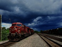 CPKC 119 (with CN 372 passing at right) is stopped under stormy skies as they build their train.