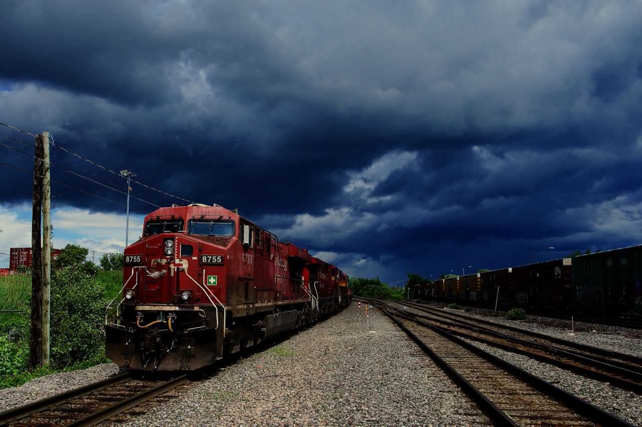 CPKC 119 (with CN 372 passing at right) is stopped under stormy skies as they build their train.