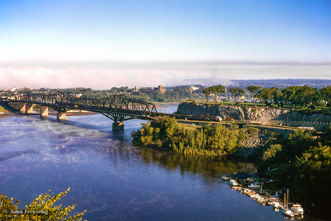 CPR no. 8, "The Dominion," rolls across the Ottawa River on the Alexandra Bridge about one mile out from Ottawa Union Station alongside the Rideau Canal.  In less than three years, passenger service to Canada's capital will be relocated to the present Union Station, located south of the downtown.  The Alexandra Bridge still stands today, in use by vehicles and pedestrians.  It is due to be replaced in the near future.Scan and editing by Jacob Patterson.