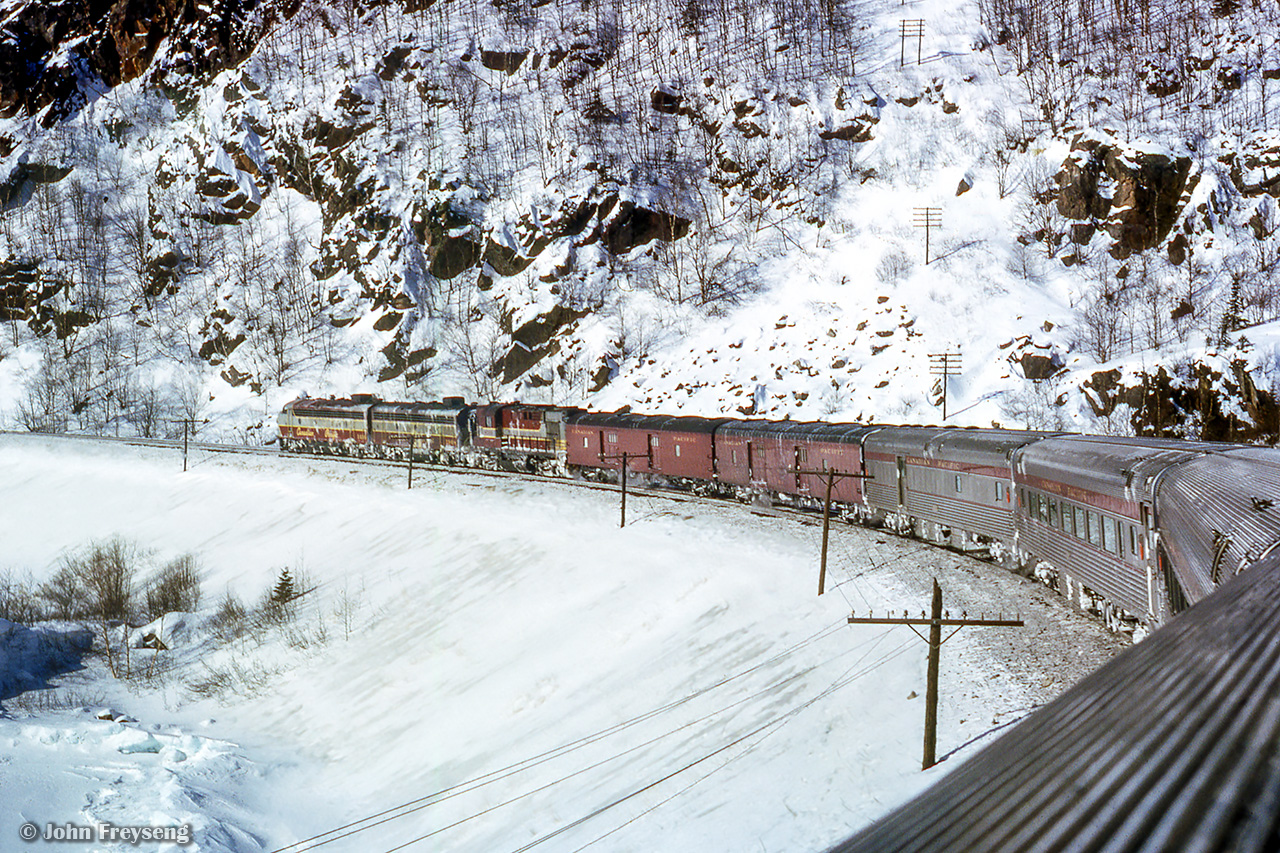 Canadian Pacific number 1, The Canadian, rolls west through the Canadian Shield north of Lake Superior.  Just a few miles west of Marathon, the classic consist negotiates a turn near the bay of Port Munro.  One of many scenes taken along this Toronto - Winnipeg - Fargo - Minneapolis - Chicago - Toronto journey, over five different railroads.Scan and editing by Jacob Patterson.