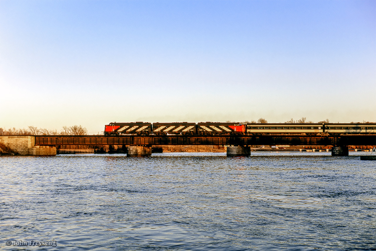 CN Rapido 64 throttles up rounding the curve through Trenton Junction, crossing the Trent River en route to Montreal. Scan and editing by Jacob Patterson.