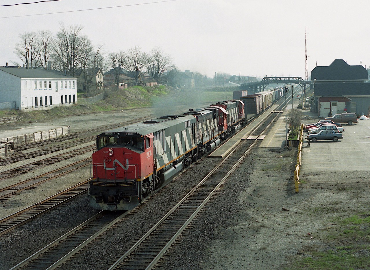 For me it was rather fortunate to have the hazy sky that prevailed on this day. The shadows of the westbound morning #393 as a result were much less harsh.  And a nice power combination.  CN 2106, 2025 and 2316 seen here passing the Woodstock VIA station. The leader, a BBD HR616 was one of a model that was quite unreliable, and most of them barely lasted 15 years, whereas the MLW C-630M and M-636 which followed lived out a long life, and delighted the fans...much more so than those who operated them. All units off the roster by 1998.