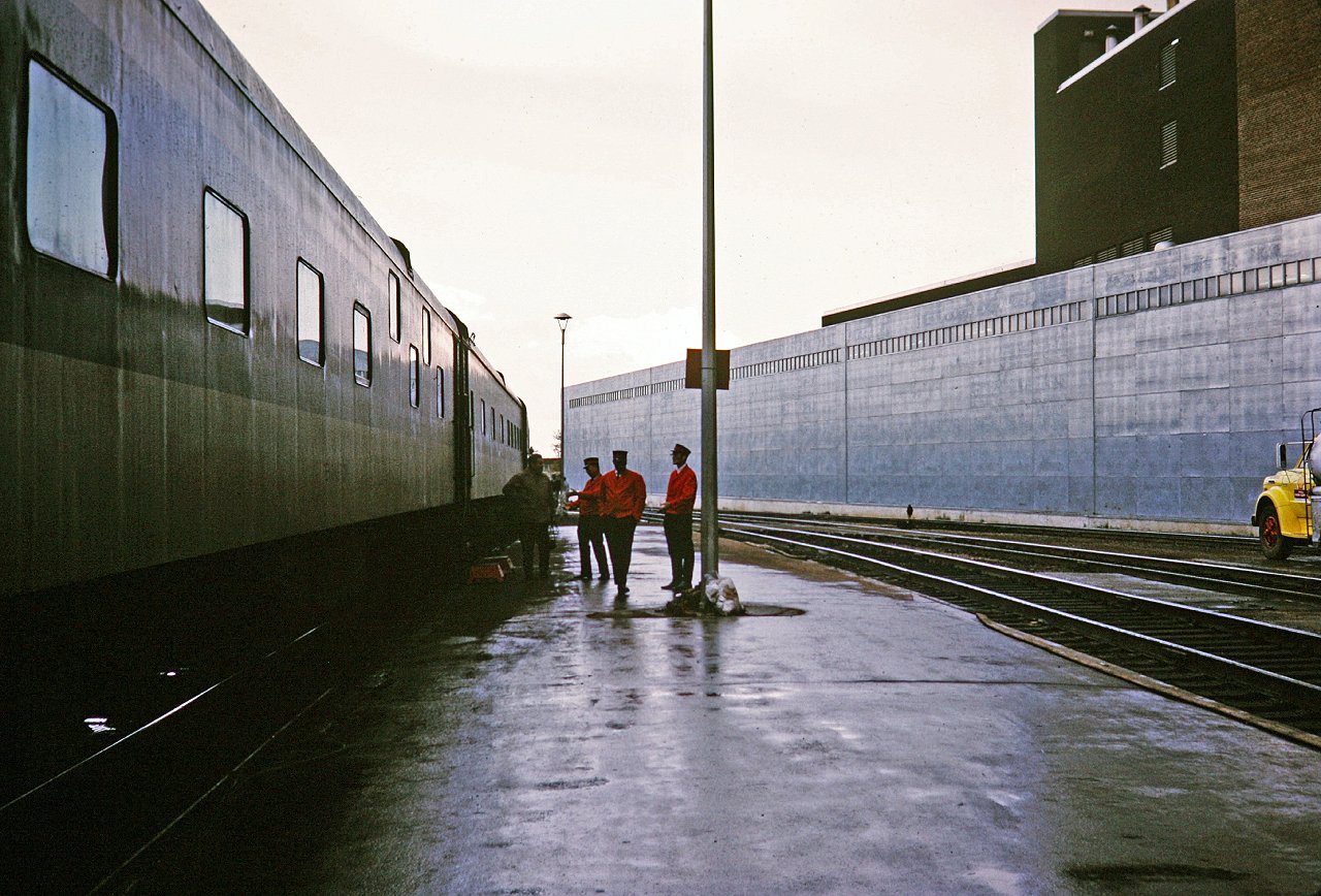 The rain has stopped but it is still a grey miserable day as the Super Continental gets serviced during its stop in downtown Edmonton. The garbage has been removed and the porters shoot the breeze in the background. Our family was traveling to BC from Toronto. Our E series sleeping car is on the left, but the name is not legible. My Mother took this shot and I'm always amazed with the the composition and the pop of color in the center.