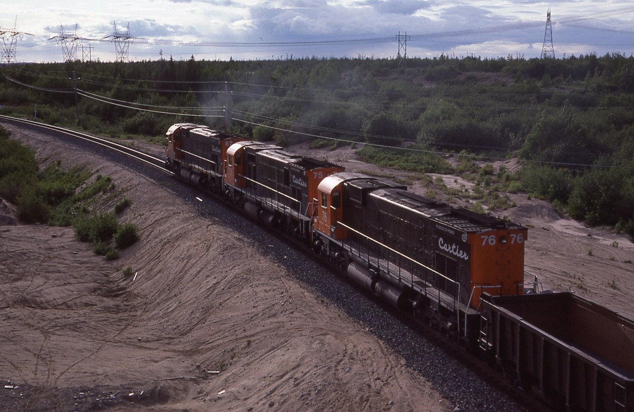 "Off into the Sunset".  I rather like this shot which was taken off the Hwy 138 bridge just north of town if I remember correctly.  Cartier 87, 75 and 76 are off into the north, destination Mont-Wright.
It would be 30 years before these big MLW M-636's would go off into their private 'sunset'; with #87 (x-CN 2331) and 76 being sold to the scrapper in 2011. The other unit lived onward, recently noted as WNYP 638.