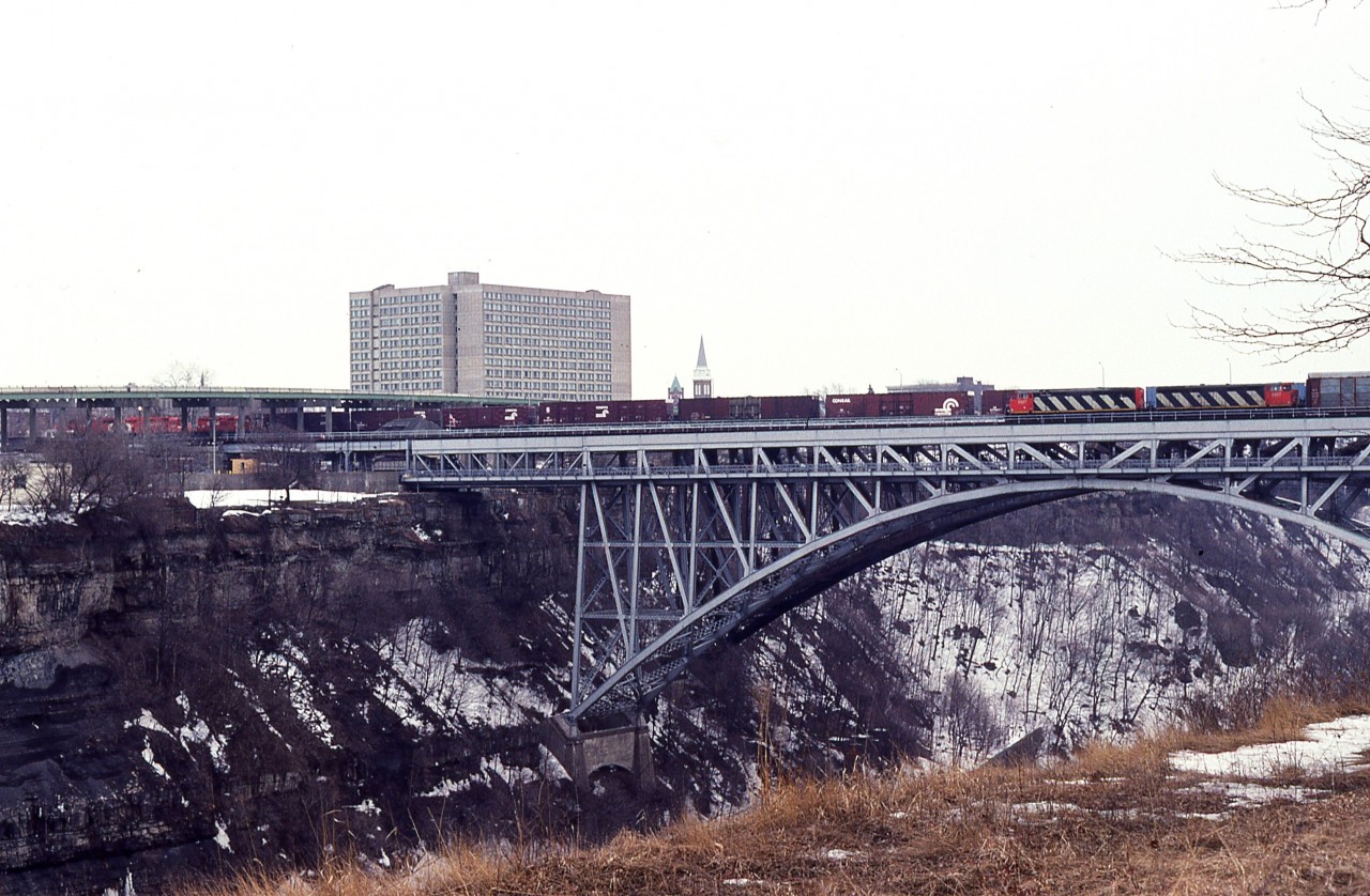 Going thru old slides, I came across this one.  I honestly do not remember taking it.  It appears I was driving southward along the parkway and saw that I had missed CP going over the old Michigan Central bridge. And, holy (bleep!) here comes CN !!!!  It looks as though I jumped out and ran to get a shot, and if I have a follow-up image I haven't found it.
But the scoop is, a train on each bridge at the same time!!!  The CP was probably a regular but the CN only happened due to  work on the International Bridge in Fort Erie and this pair of 5400s was a resulting detour train.

All I know as I was down in the Falls as often as I had time to as the rail traffic on the Whirlpool was a rare thing, save for the odd local and the AMTK.