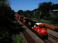 CN 120 has a trio of GEs up front as it passes well cars stored on the Transfer Track.