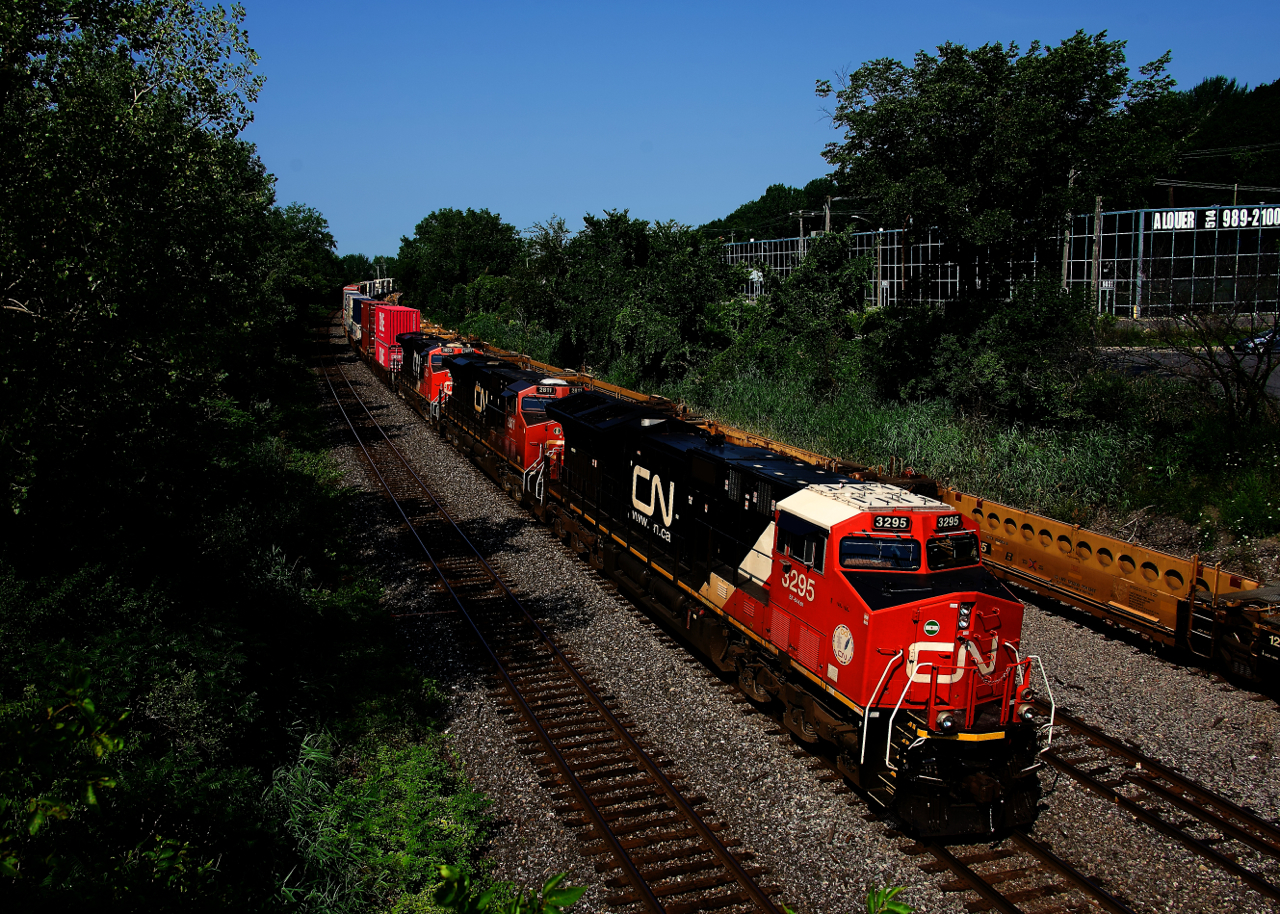 CN 120 has a trio of GEs up front as it passes well cars stored on the Transfer Track.