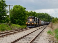 GIO's Tillsonburg job comes to a stop on the west side of Tillsonburg to lift a tank car from storage out of XE85 at right.  With its thirteen car train together in a few minutes, the train will depart for St. Thomas.  Much of the morning had been spent sorting a cut of around fifty storage cars, departing shortly after noon.

<br><br>Just ahead of the train, an old switch tie can be seen jutting out to the left with an out of service GRS switch circuit controller still in place.  This is one of the few remnants of this location once carrying the name "Tillsonburg Junction," where the Cayuga and Burford Subs once joined, <a href=https://ontariorailwaystations.wordpress.com/wp-content/uploads/2024/04/tillsonburg-junction-1.jpg>including a station.</a>  The Burford Sub would be abandoned from Burford to Tillsonburg North in  1989, leaving the trackage within town intact for a few more years before removal. 