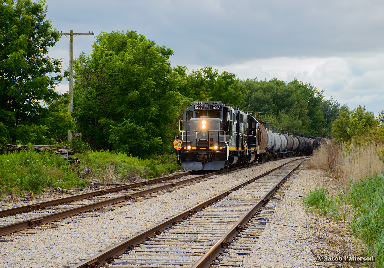 GIO's Tillsonburg job comes to a stop on the west side of Tillsonburg to lift a tank car from storage out of XE85 at right.  With its thirteen car train together in a few minutes, the train will depart for St. Thomas.  Much of the morning had been spent sorting a cut of around fifty storage cars, departing shortly after noon.

Just ahead of the train, an old switch tie can be seen jutting out to the left with an out of service GRS switch circuit controller still in place.  This is one of the few remnants of this location once carrying the name "Tillsonburg Junction," where the Cayuga and Burford Subs once joined, including a station.  The Burford Sub would be abandoned from Burford to Tillsonburg North in  1989, leaving the trackage within town intact for a few more years before removal.