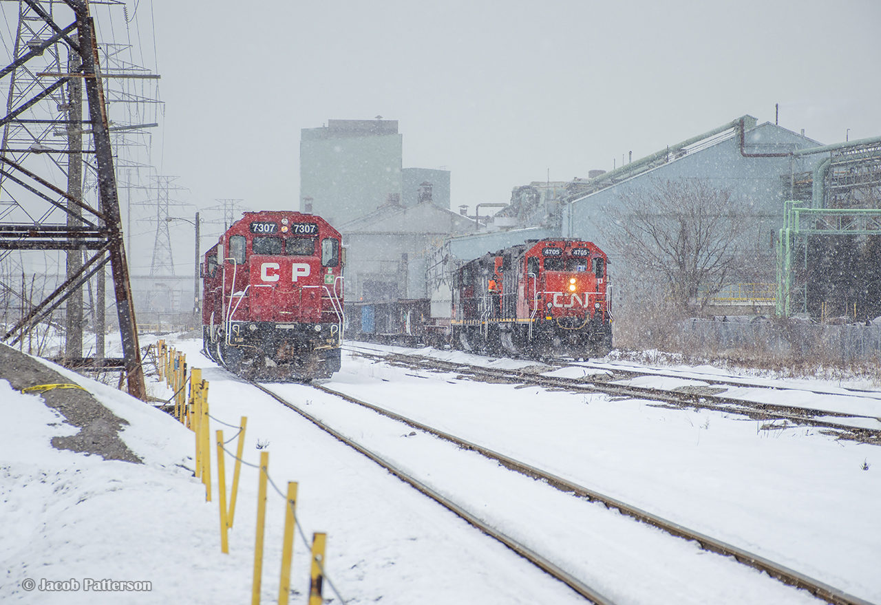 An afternoon snowfall has kicked up in Hamilton, where jobs from both class 1s are seen around the interchange.  At right, CN's 0700 job is lifting traffic from CP, along with cars from Stelco, Mana, and Parkland Fuels, while TH11 returns down the Belt Line from Kinnear, bound for Strathearne Yard.