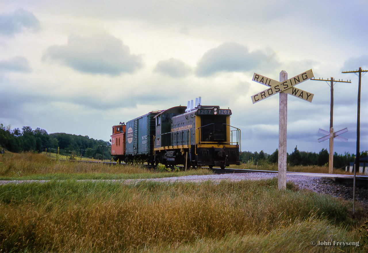 A southbound wayfreight behind GMD SW1200RS 1207 hustles south with a single NYC boxcar in tow at Franklin Road crossing, long since removed.Scan and editing by Jacob Patterson.