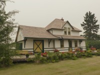 The Canadian Northern Railway Station is a one and one-half storey building situated on one lot on Railway Drive in the Town of Smoky Lake. The site is adjacent to the abandoned railway right-of-way that now serves as a portion of the Iron Horse Trail, a regional recreational corridor. The building is a Standard Third Class station constructed in 1919 according to Plan 100-72. It features a white stucco exterior with green trim, a hipped roof over the main station area, two gabled wall dormers on the front and back elevations, and a low-pitched gable roof over the baggage area. A wide eave with large brackets extends along the platform.(source:historicplaces.ca) Photo was taken on a day when forest fires in Alberta caused the smoky skies.