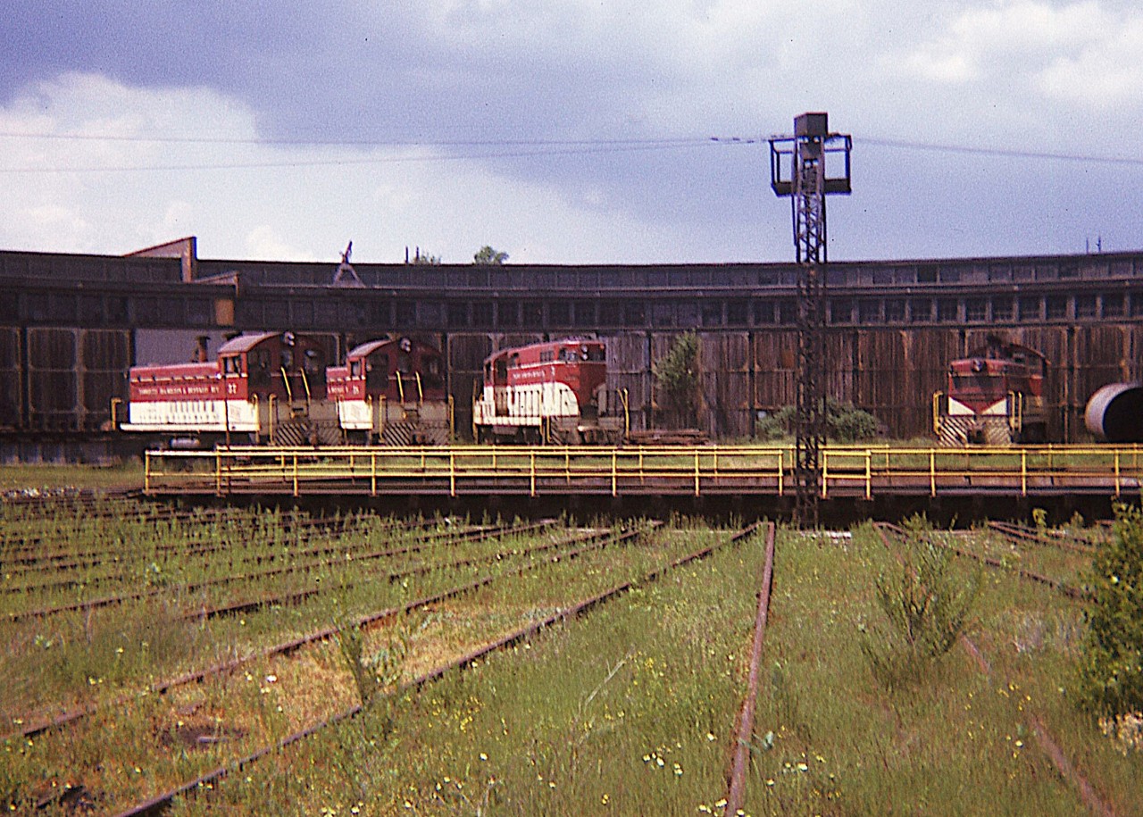 Fifty years has gone by since I snapped this photo of a few slumbering TH&B locomotives in what was a rather idyllic setting.  Hard to believe this was a busy railroad in the western reaches of Hamilton.
As most of you know, the railroad is long gone, the shop building & roundhouse are long gone, and the theme of this image is, well,  just for the memories............