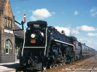 The old Canadian National Brampton Station (built by Grand Trunk (GTR) in 1907 to replace the original 1855 station) has seen a lot of changes over the years, some for the better, others less so. The transition from steam to diesel in the 1950's, the introduction of <a href=http://www.railpictures.ca/?attachment_id=36003><b>GO Transit commuter service</b></a> in 1974, <a href=http://www.railpictures.ca/?attachment_id=852><b>VIA</b></a> taking over passenger services from CN in 1978, <a href=http://www.railpictures.ca/?attachment_id=11147><b>extra station platforms</b></a> for expanded GO service, and more. At one point, Ryerson University was even going to build its campus right next to the station, in the parking lot to the west (thankfully, this seems to have been nixed for the Ryerson/TMU medical school at the Bramalea Civic Centre). It also outlasted nearby competitor <a href=http://www.railpictures.ca/?attachment_id=33072><b>CPR's station</b></a> after CP discontinued its passenger service in 1970 (but the station was thankfully saved, and reconstructed after many years).<br><br>During the final years of the steam era in Canada, one of CN's famed 4-8-4 "Northern" steam engines 6200 pulls into Brampton Station on the head of a short 4-car westbound passenger train in October 1958. The fall sun angle suggests this is an afternoon or late afternoon train (maybe Toronto-London train #111 via Stratford, scheduled to be at Brampton just before 2pm). Note the old train order signal, and CN Telegraph/Cable Office sign by the ticket office window. In 1958, the CN Brampton Sub (renamed the Halton Sub in 1965) was still single track with ABS signals, and the second track here was the siding that ended east of the station as-shown.<br><br>Protected by a federal historical designation in 1992, Brampton Station (now called "Brampton Innovation District GO Station" for the next 10 years, thanks to city council...) will see further changes nearby as the houses across the tracks along Railroad Street are redeveloped, a possible third main track for expanded all-day-two-way <a href=http://www.railpictures.ca/?attachment_id=10415><b>GO service</b></a>, and a future LRT line may be knocking at its doorstep in the near future when the nearby Brampton Transit downtown terminal is redeveloped (that replaced an old coal dealer, note the siding on the right to the coal unloading trestle).<br><br><i>Original photographer unknown (unmarked duplicate), Dan Dell'Unto collection slide.</i>