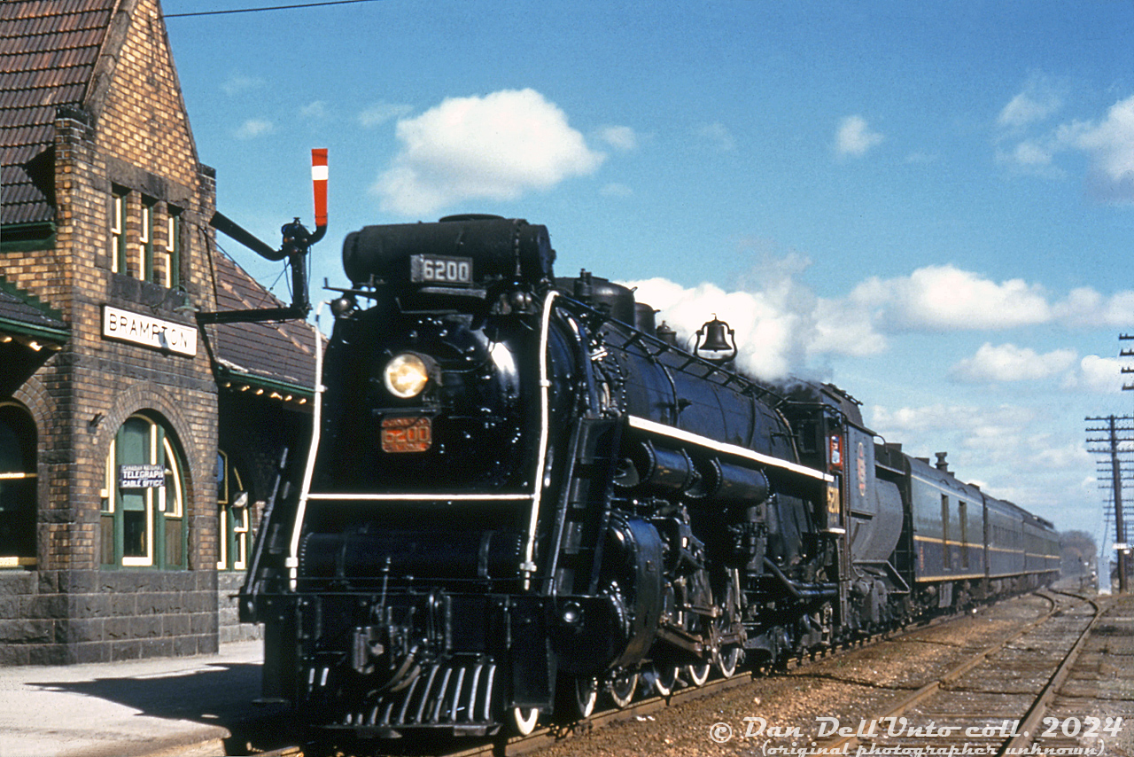 The old Canadian National Brampton Station (built by Grand Trunk (GTR) in 1907 to replace the original 1855 station) has seen a lot of changes over the years, some for the better, others less so. The transition from steam to diesel in the 1950's, the introduction of GO Transit commuter service in 1974, VIA taking over passenger services from CN in 1978, extra station platforms for expanded GO service, and more. At one point, Ryerson University was even going to build its campus right next to the station, in the parking lot to the west (thankfully, this seems to have been nixed for the Ryerson/TMU medical school at the Bramalea Civic Centre). It also outlasted nearby competitor CPR's station after CP discontinued its passenger service in 1970 (but the station was thankfully saved, and reconstructed after many years).

During the final years of the steam era in Canada, one of CN's famed 4-8-4 "Northern" steam engines 6200 pulls into Brampton Station on the head of a short 4-car westbound passenger train in October 1958. The fall sun angle suggests this is an afternoon or late afternoon train (maybe Toronto-London train #111 via Stratford, scheduled to be at Brampton just before 2pm). Note the old train order board signal, and CN Telegraph/Cable Office sign by the ticket office window. In 1958, the CN Brampton Sub (renamed the Halton Sub in 1965) was still single track with ABS signals, and the second track here was the siding that ended east of the station as-shown.

Protected by a federal historical designation in 1992, Brampton Station (now called "Brampton Innovation District GO Station" for the next 10 years, thanks to city council...) will see further changes nearby as the houses across the tracks along Railroad Street are redeveloped, a possible third main track for expanded all-day-two-way GO service, and a future LRT line may be knocking at its doorstep in the near future when the nearby Brampton Transit downtown terminal is redeveloped (that replaced an old coal dealer, note the siding on the right to the coal unloading trestle).

Original photographer unknown (unmarked duplicate), Dan Dell'Unto collection slide.