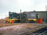 Chesapeake & Ohio GP7's 5730 and 5744 (built by GMD and EMD respectively, in 1951), gleam in the evening light outside the old wooden enginehouse at Chatham in 1970. <br><br> Due to tax/duty rules at the time, a handful of US railways including C&O, NYC and Wabash purchased locomotives from EMD's Canadian operation, General Motors Diesel, in London Ontario, for their lines in Canada. C&O acquired units 5720-5738 from GMD (5720-5729 later sold to the New York Central RR for their Canadian operations in 1956, as NYC 5818-5827). <br><br> C&O 5744, built by EMD, was one of a handful of US-built GP7's transferred to the C&O's Canadian operations. The Geep fleet worked C&O's lines in southern Ontario for many decades and into the 1980's under CSX, until <a href=http://www.railpictures.ca/?attachment_id=18272><b>mass retirement in the mid-1980's</b></a>.<br><br><i>Original photographer unknown, Dan Dell'Unto collection slide.</i>