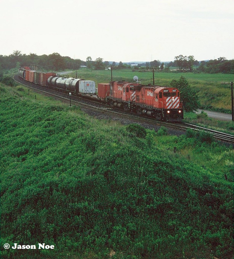 A short CP eastbound is seen at the east siding switch Orrs Lake on the Galt Subdivision powered by C-424’s 4227 and 4201. If memory serves, the photo was taken from atop a large gravel hill.