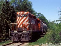 "Come to Marineland, where you can touch a whale in Friendship Cove, see the dolphins do their dolphin thing, and...shoot a train too?". Why yes!<br><br>CP Rail GP9u 8212 on a short local handles a single covered hopper inside Marineland, sitting by the switch to the Washington Mills siding at the main access road inside the amusement park grounds. The Geep is working the CP Chippawa Industrial Spur (around Mile 13.50) that runs south from CP's Hamilton Sub (the old PC/CR Canada Division line, aka the CASO, and now CP's Montrose Spur) down to the Welland River in Chippawa, where the line ends by the only other customer, Saint Gobain. A 1992 CP timetable specifically states only single unit operation is permitted on the entire spur, with a speed restriction of maximum 5 mph. The date of this blank, unlabeled slide is unknown, but judging by other photos of 8212 it was taken sometime in the 1990's.<br><br>Since Marineland is private property, gates block off this portion of the rail line through the park at both ends. Access here for a photo or two would have only been possible by paying admission to Marineland to get into the park (Marineland was the latecomer, having been built in the early 1960's along one side of the line, but it looks like they only began to expanded their park to the property across the tracks in the 1970's-80s).<br><br>This was once the old Michigan Central Niagara Branch that ran from Fort Erie to Niagara-on-the-Lake. A hydro corridor also rain south alongside part of it here. Research shows the line south of Chippawa to Fort Erie was abandoned in 1941, and the remaining section served as a short spur from there to the mainline to access a few local customers. The line passed through New York Central, Penn Central and Conrail ownership until CP acquired the old CASO from Conrail in the 1980's. When the main CASO line (CP Hamilton Sub) through the downtown Niagara Falls tourist area was lifted in 2001, it was removed only as far south as the switch to the Chippawa Industrial Spur, letting CP locals continue to have access to serve Washington Mills and Saint Gobain.<br><br>With all the controversy surrounding Marineland and its recent change of ownership, it should be interesting to see what becomes of the place and how this line fairs in the future.<br><br><i>Original photographer unknown, Dan Dell'Unto collection slide.</i>